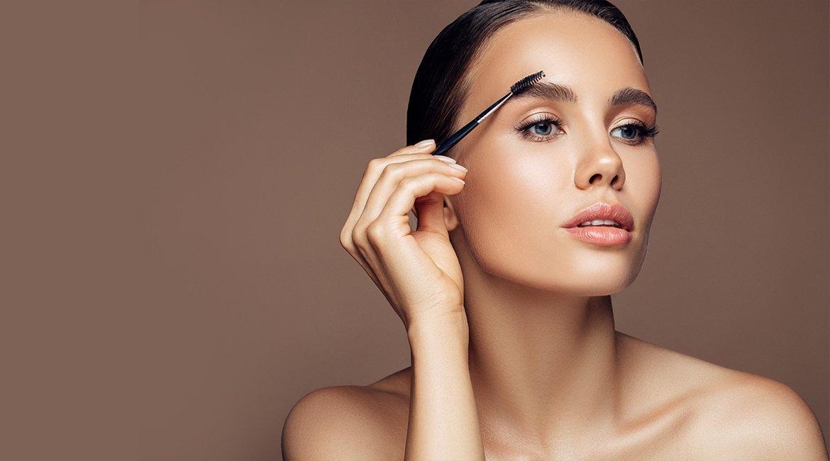 Junge Frau trägt ihr Augenbrauen-Make-up mit einem Brush auf